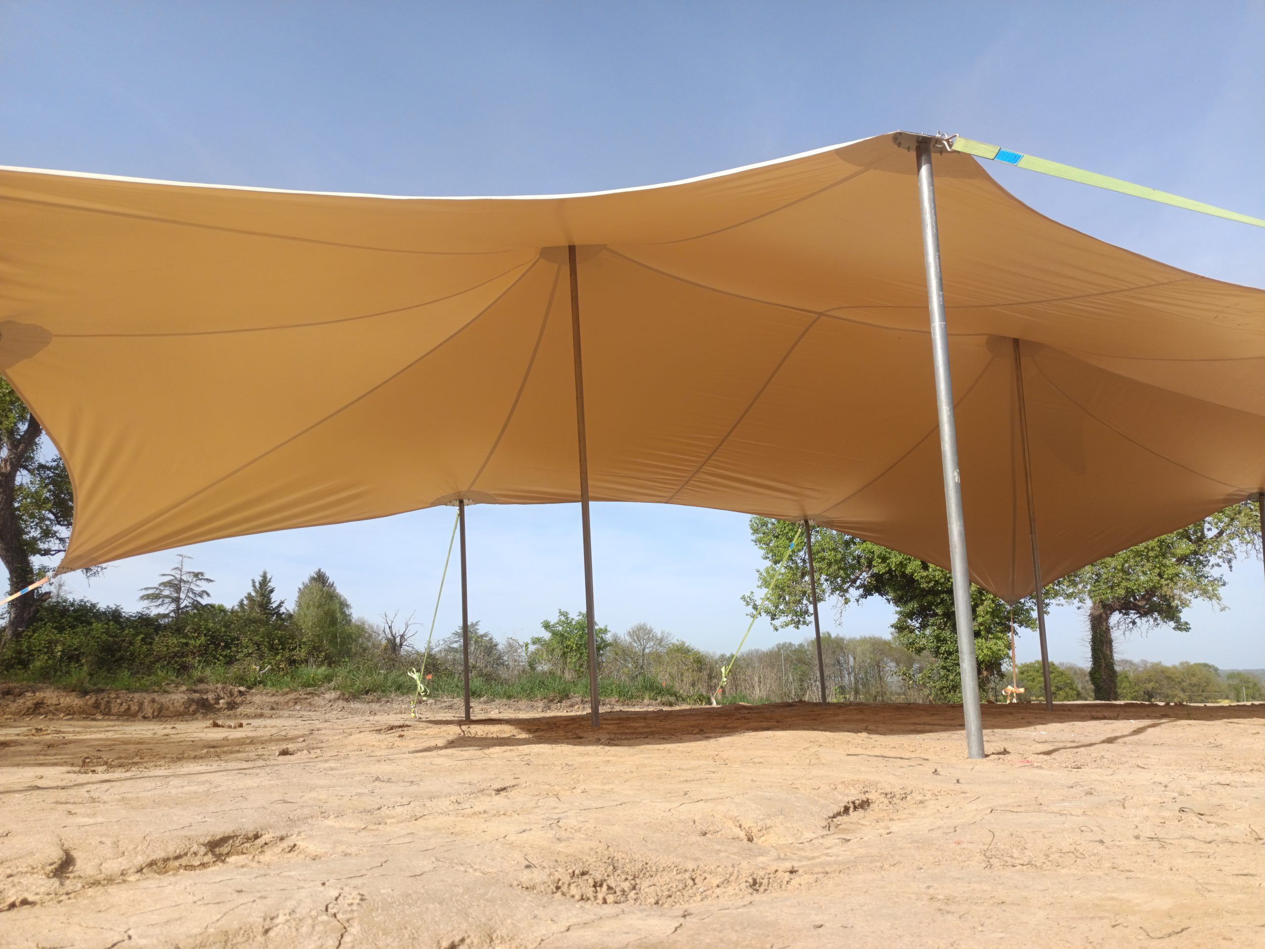 Vue sous une tente nomade beige avec mâts de soutien et toile tendue