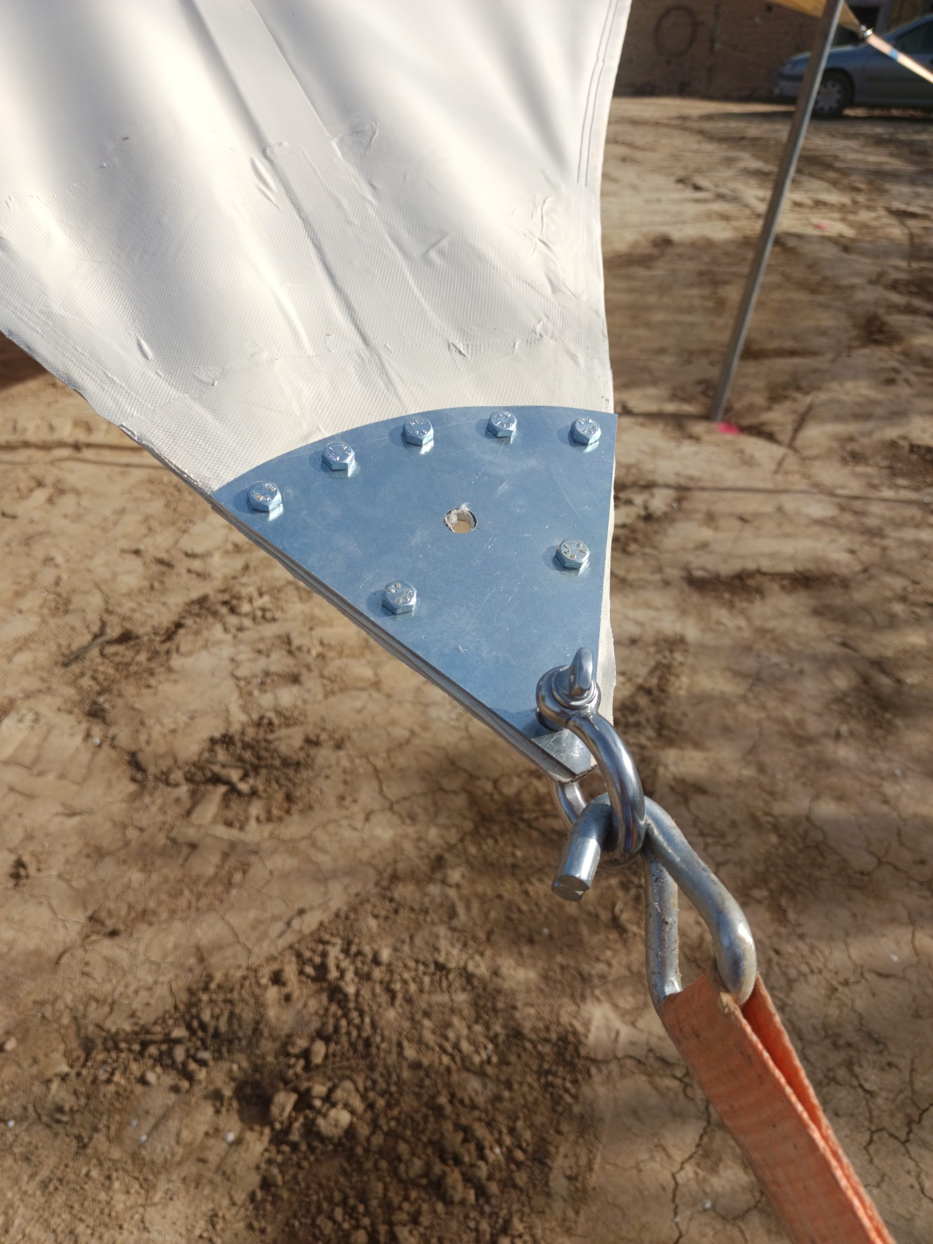 Renfort métallique triangulaire fixé à la toile d'une tente nomade avec anneau et mousqueton de tension
